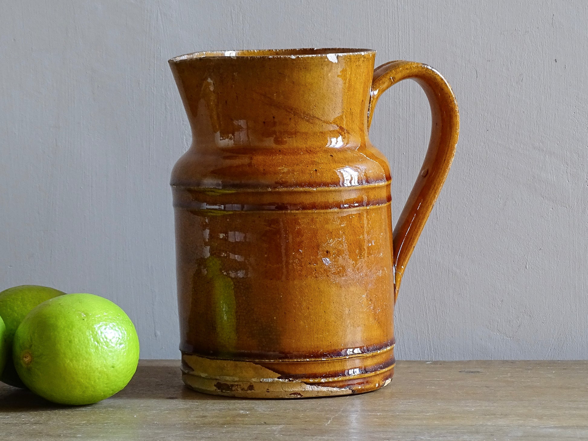 Rustic French antique pottery jug with an orange glaze. Glazed ceramic pitcher from Savoie. Savoyard pottery jug with a handle and spout. 