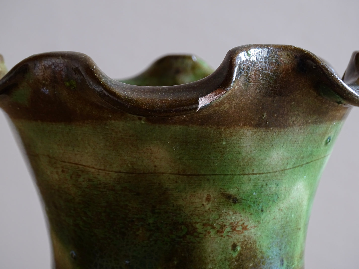French vintage glazed terracotta vase from Castelnaudary. The ceramic vase has a textured green and brown glaze. It has a crimped rim and crackled glaze on the lower portion. Pottery vase for farmhouse decor.