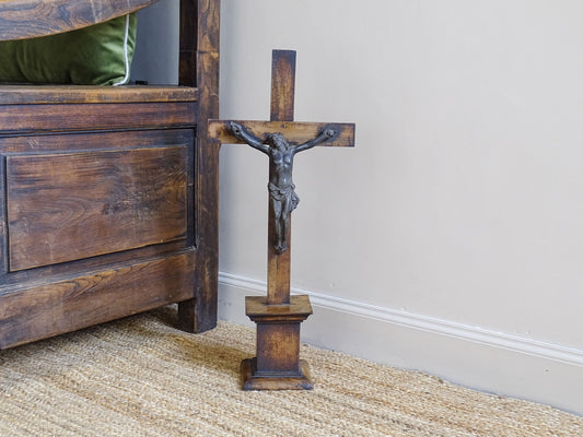 A French antique altar crucifix featuring a wooden cross with a spelter figure of Christ, mounted on a tiered wooden base. The wood has a rich patina.