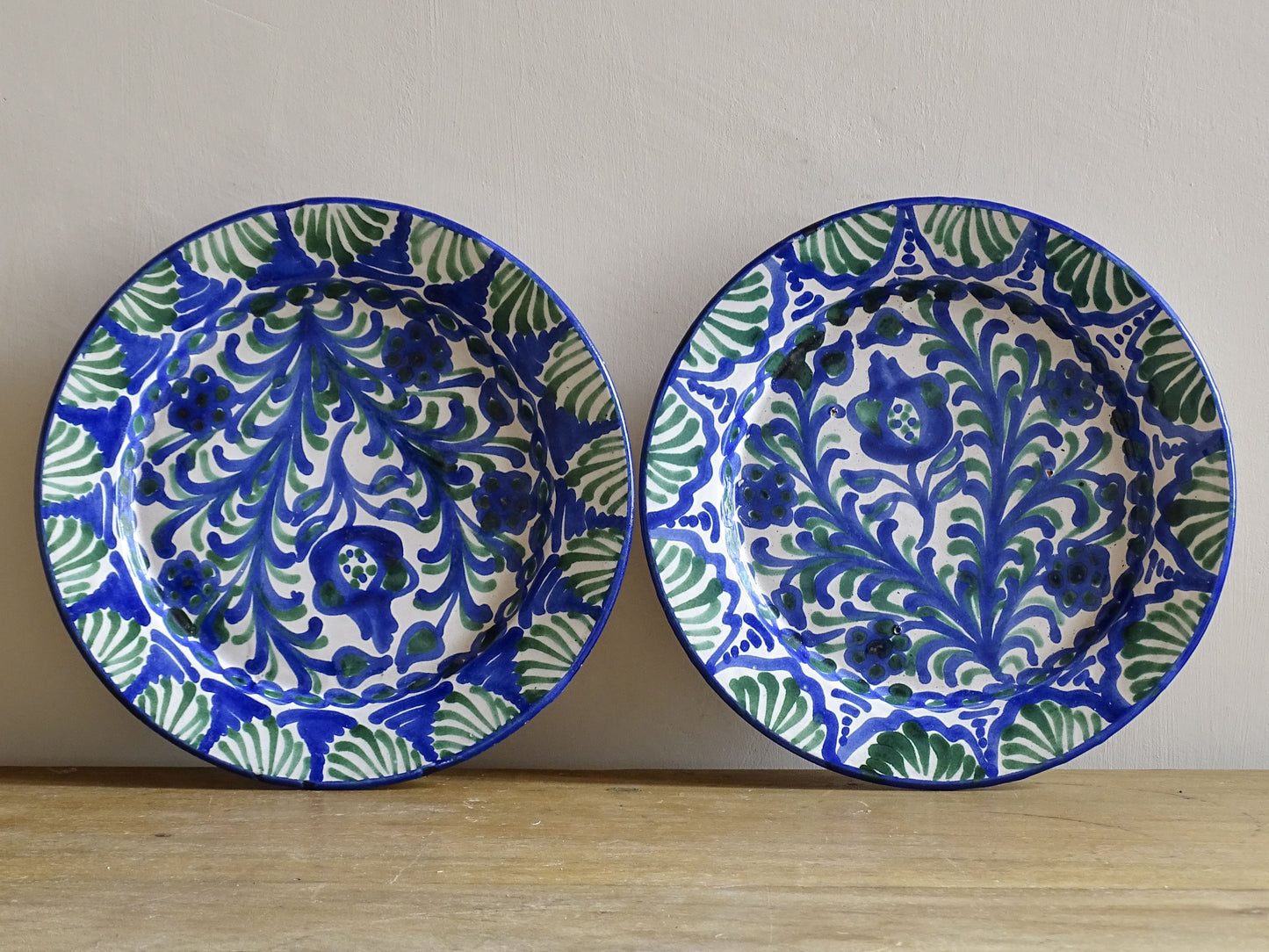 Pair of Spanish vintage Fajalauza plates, hand-painted in green and blue, decorated with flowers, leaves and pomegranates. Tin glazed terracotta plates for wall decor. 