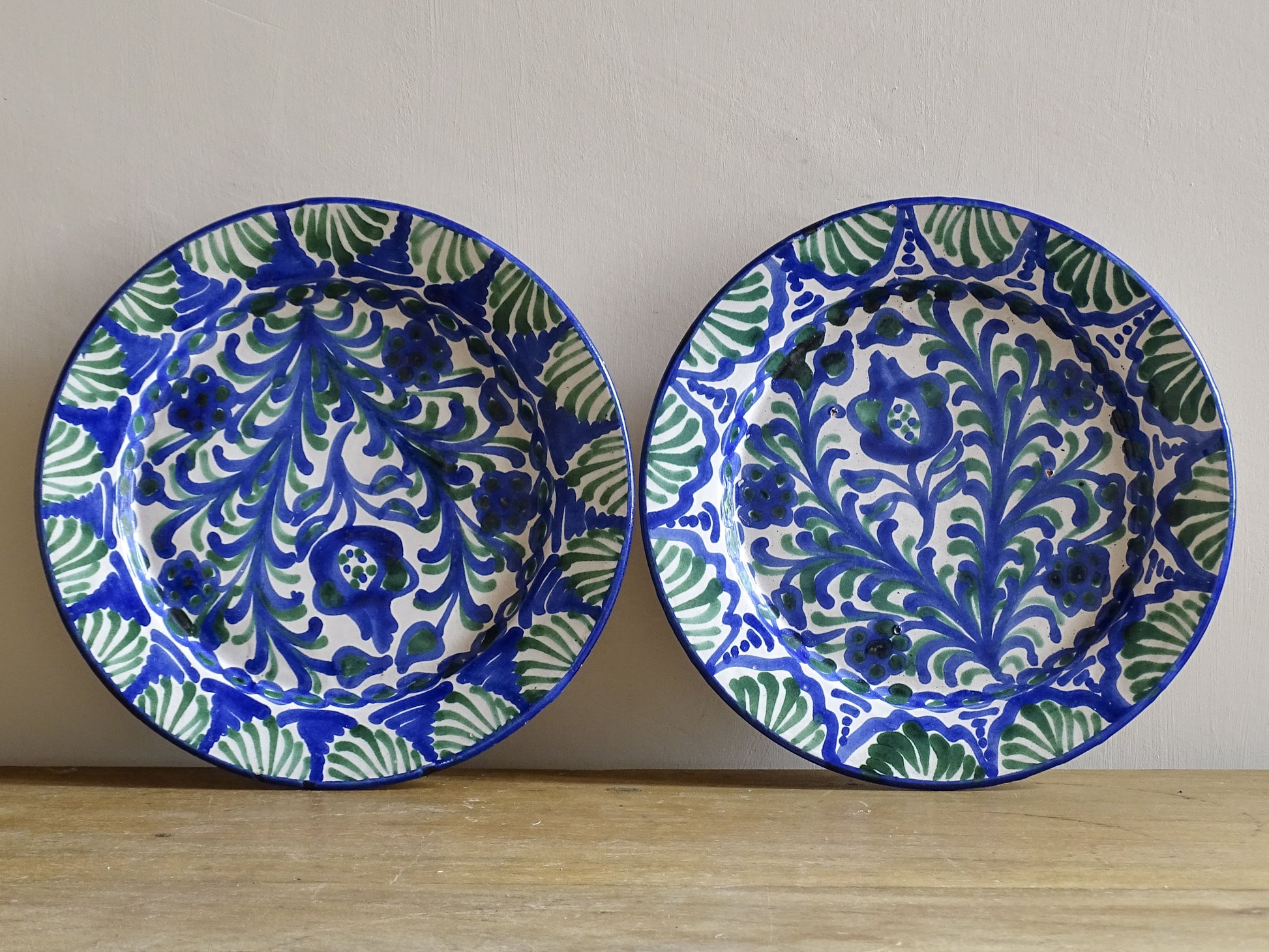Pair of Spanish vintage Fajalauza plates, hand-painted in green and blue, decorated with flowers, leaves and pomegranates. Tin glazed terracotta plates for wall decor. 