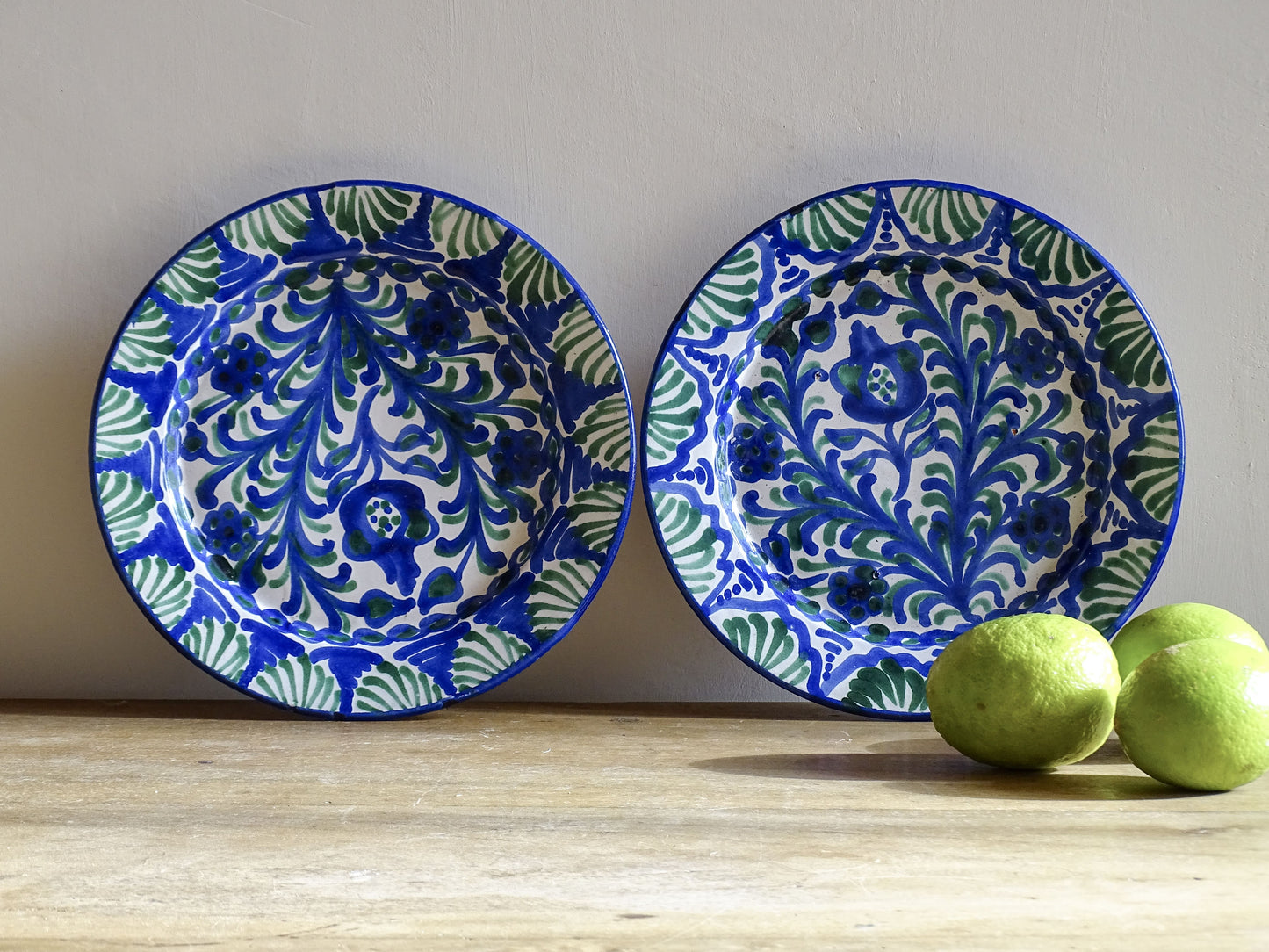 Pair of Spanish vintage Fajalauza plates, hand-painted in green and blue, decorated with flowers, leaves and pomegranates. Tin glazed terracotta plates for wall decor. 