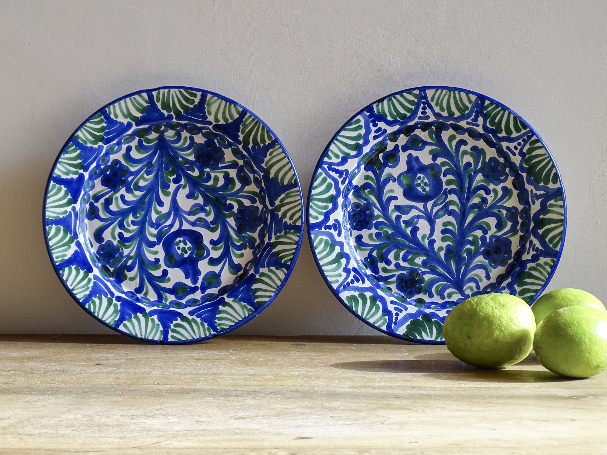 Pair of Spanish vintage Fajalauza plates, hand-painted in green and blue, decorated with flowers, leaves and pomegranates. Tin glazed terracotta plates for wall decor. 