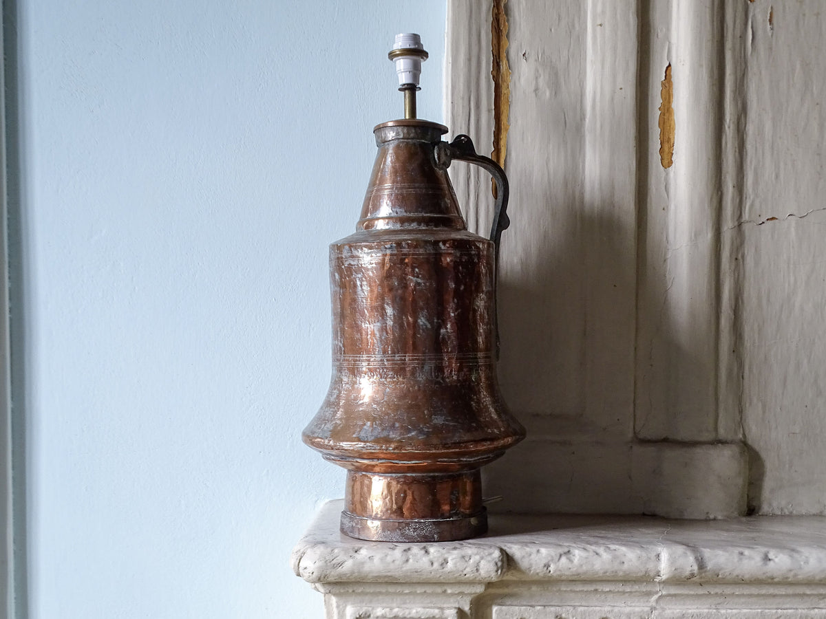 French antique copper pitcher table lamp, pictured on a country house fireplace