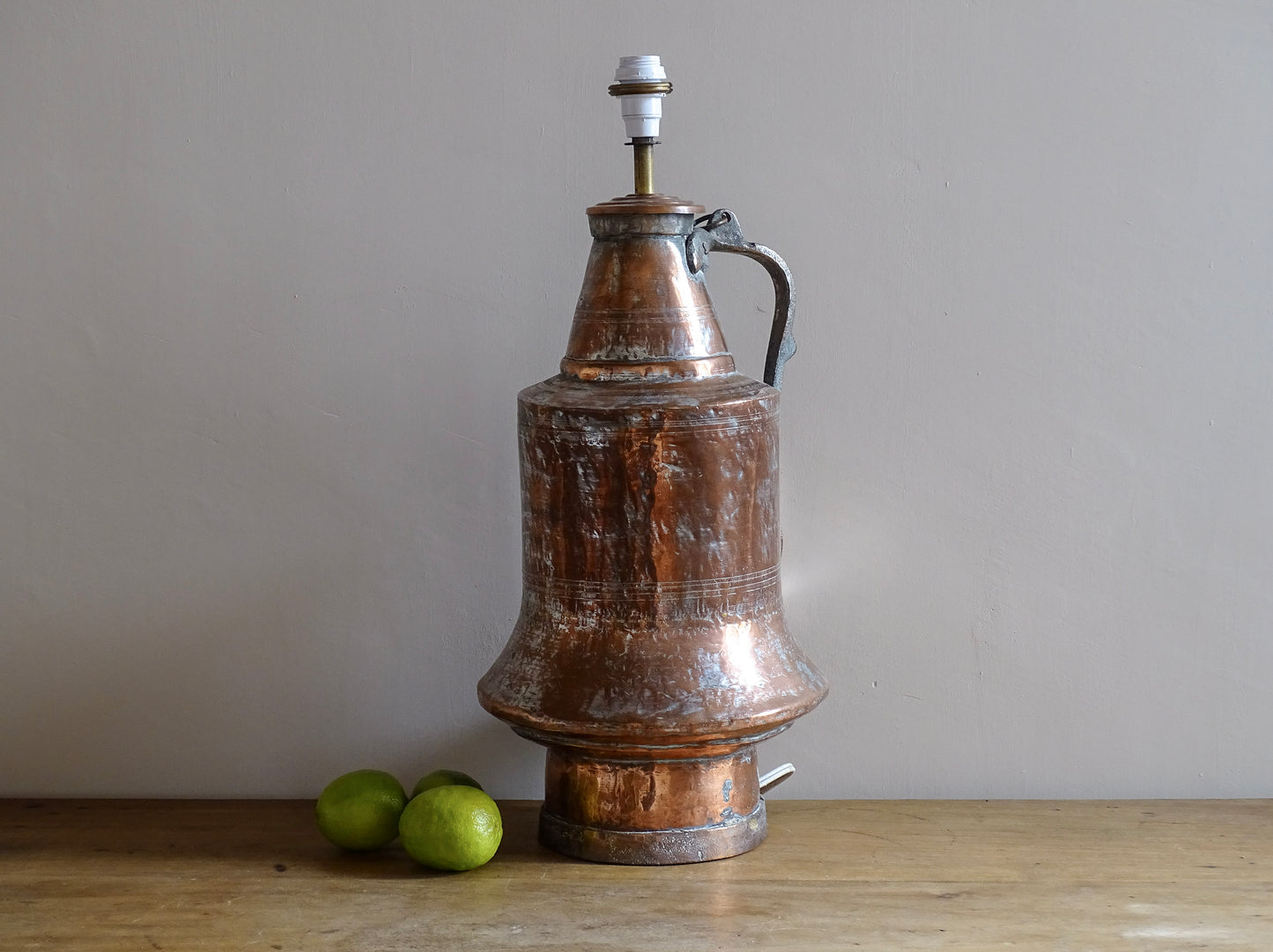 French antique copper pitcher  converted into a copper table lamp. The antique lamp has a flared base, curved handle, and surface patina.
