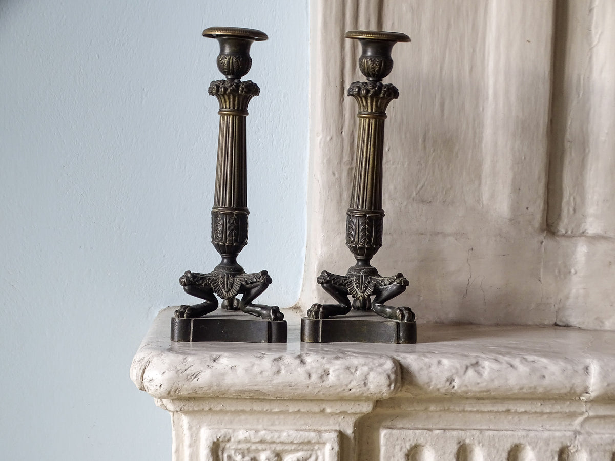 French antique bronze candlesticks with lion feet from the restoration period, displayed on a country fireplace