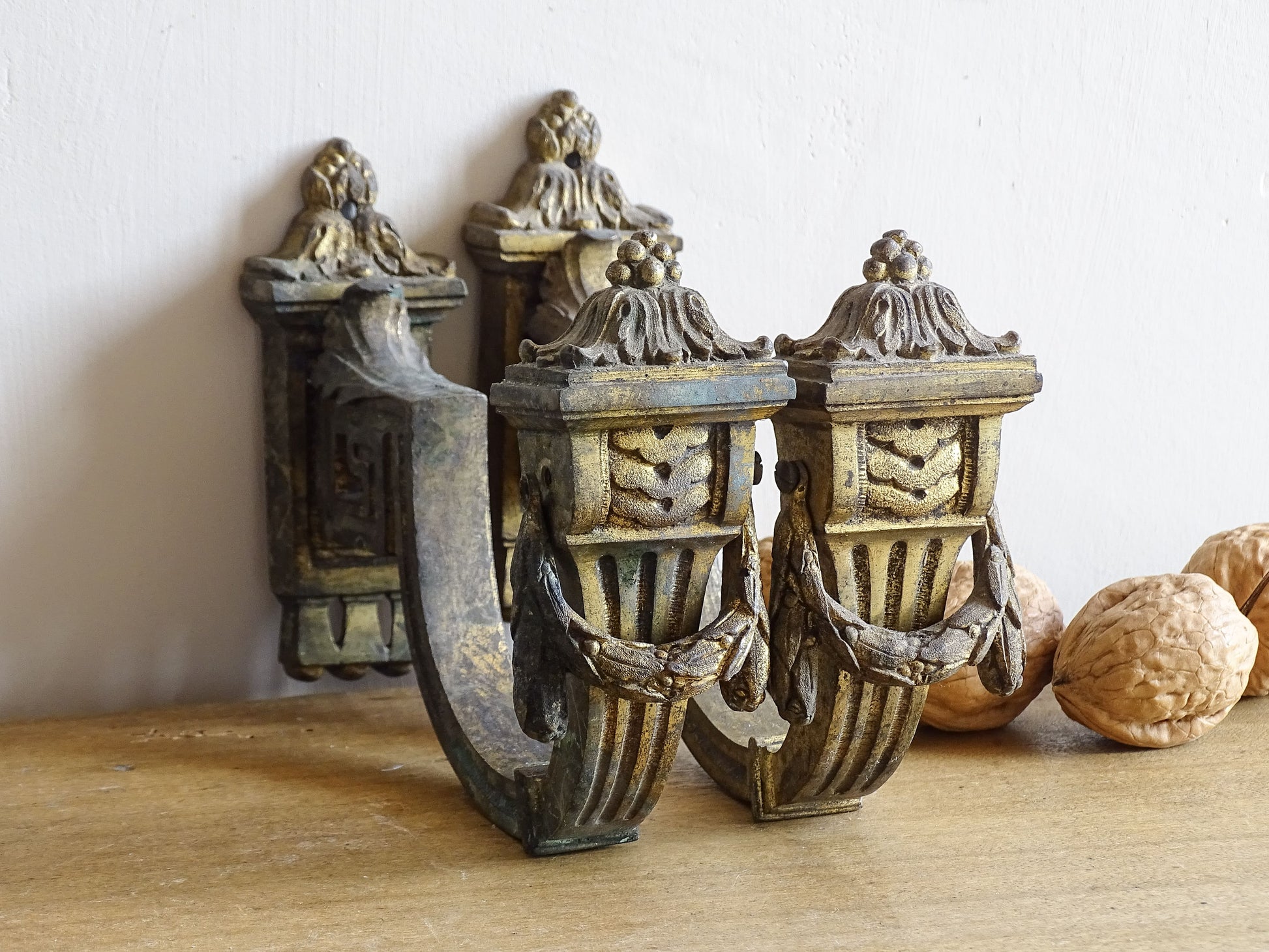 Pair of French antique curtain hooks in gilt bronze with intricate detailing. Empire style hooks with intricate acanthus leaf motifs and architectural elements.