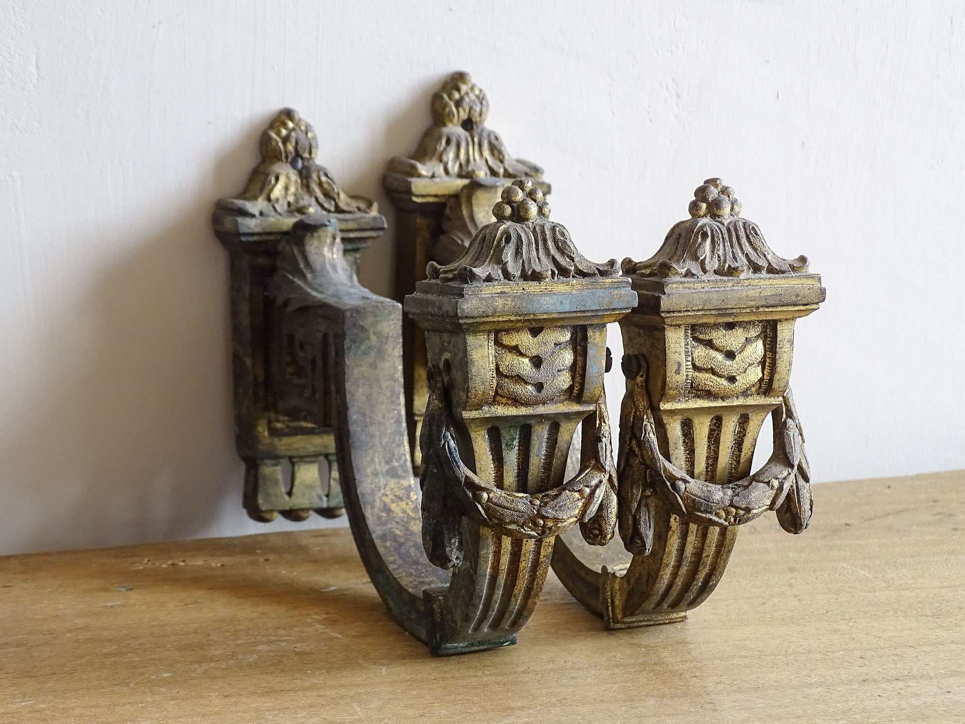 Pair of French antique curtain hooks in gilt bronze with intricate detailing. Empire style hooks with intricate acanthus leaf motifs and architectural elements.