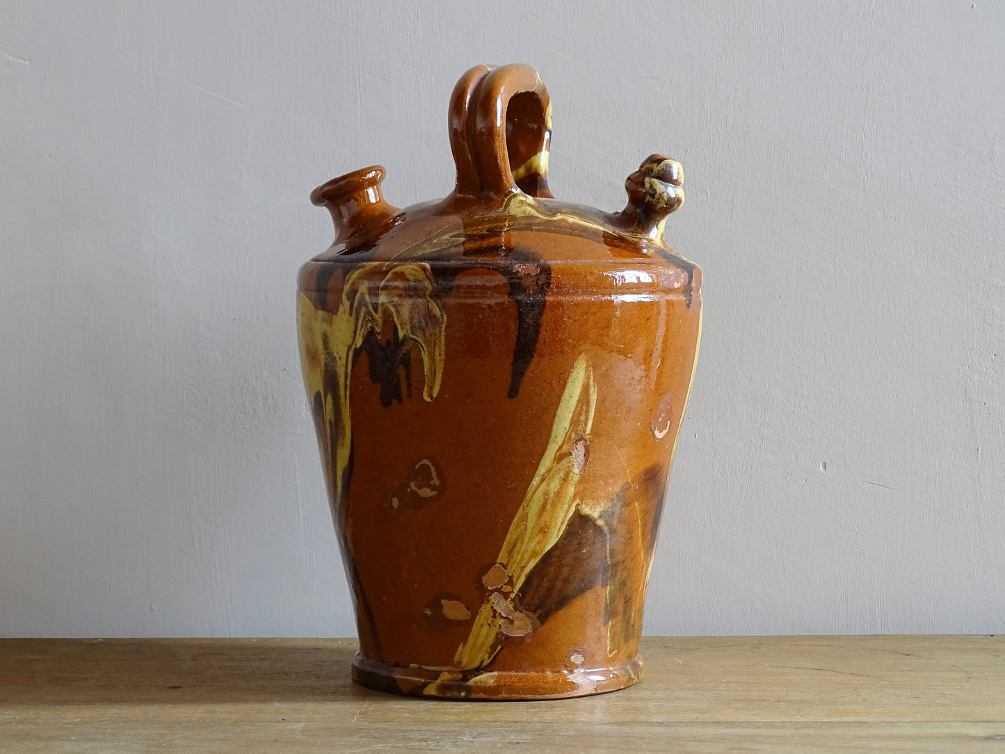 Rustic Catalan antique pottery gargoulette with a jaspé glaze in yellow or brown. The body of this marble glazed terracotta water jug has a sturdy handle to the top and two spouts.