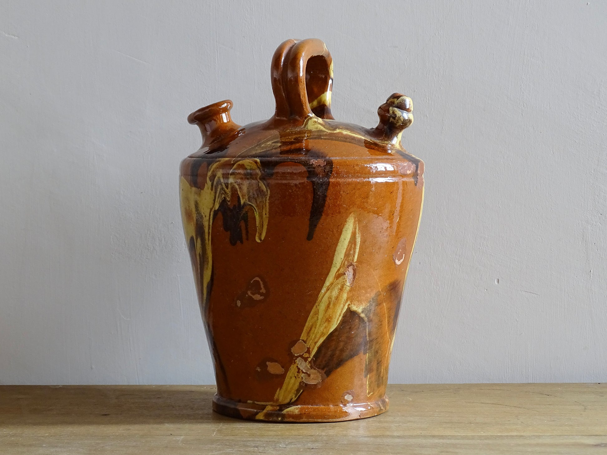 Rustic Catalan antique pottery gargoulette with a jaspé glaze in yellow or brown. The body of this marble glazed terracotta water jug has a sturdy handle to the top and two spouts.