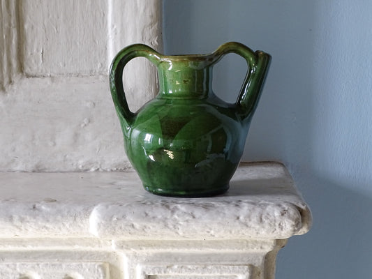 French vintage ceramic orjol jug with green glaze on an old country house fireplace