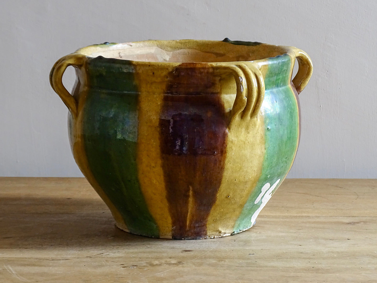 French antique terracotta planter from Castelnaudary. 19th century jardinière with a stripe drip glaze in yellow, green and brown. Antique earthenware pot with four loop handles.