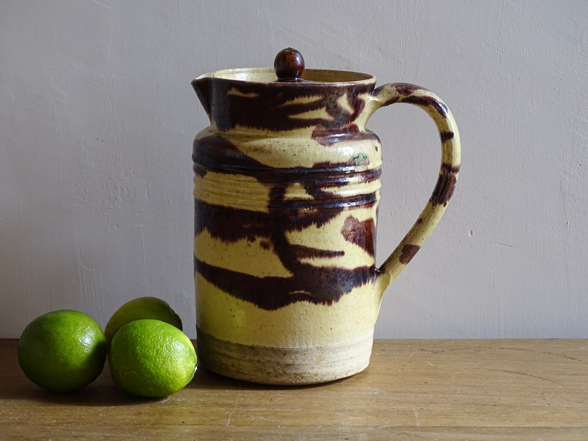 Large French antique ceramic pitcher with a lid. The glazed pottery jug has a gorgeous brown drip glaze on a yellow glazed background. 