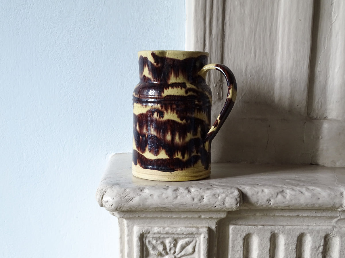 French antique ceramic pitcher from Dieulefit with yellow and brown stripe glaze pictured on a country fireplace
