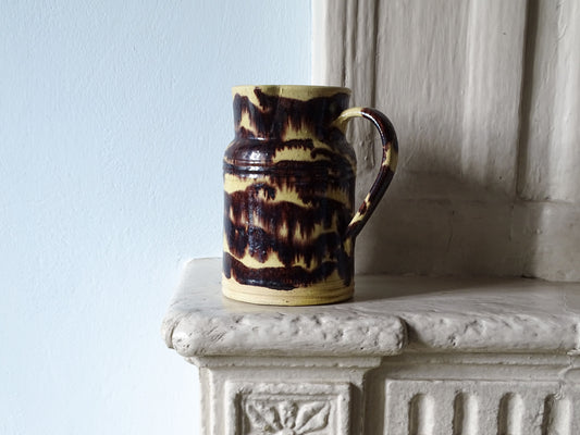 French antique ceramic pitcher from Dieulefit with yellow and brown stripe glaze pictured on a country fireplace