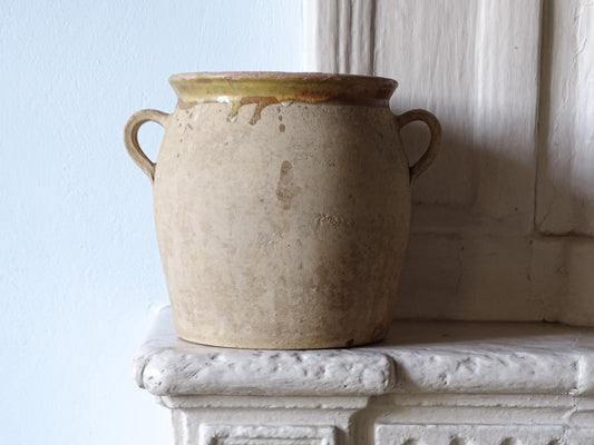 French antique confit pot with yellow glazed interior, pictured on a country house fireplace