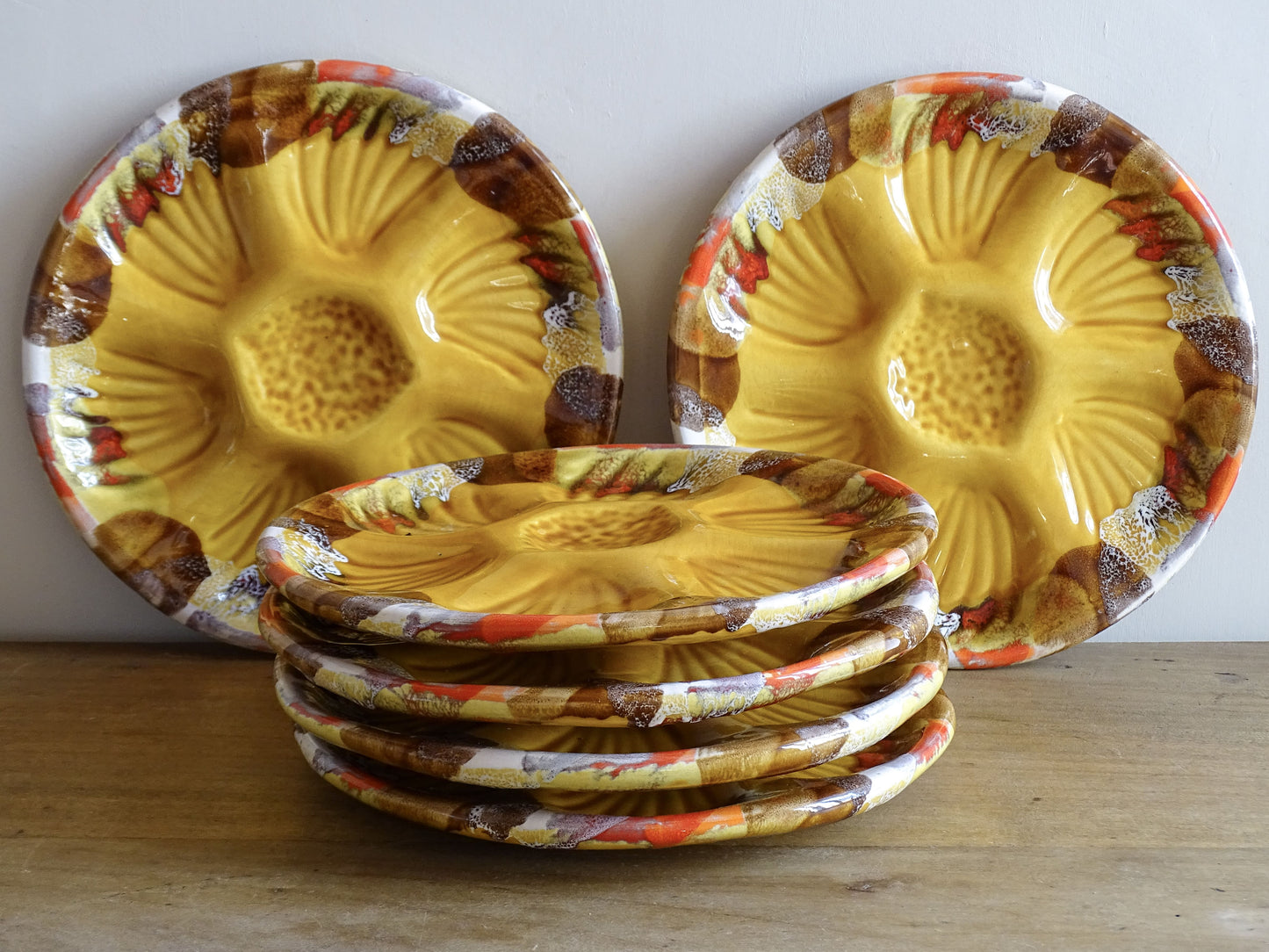 French vintage Vallauris pottery oyster plates with an ochre yellow glaze and a freeform edge in brown, red and white.