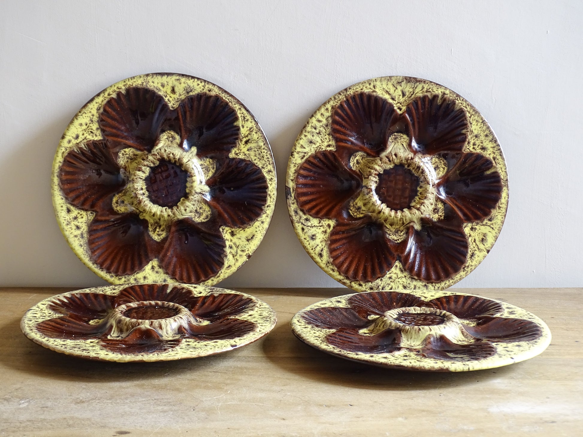 Set of four French vintage Vallauris ceramic oyster plates by Maruis Giuge with space for six oysters. They have a yellow and brown glaze.
