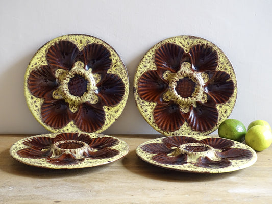 Set of four French vintage Vallauris ceramic oyster plates by Maruis Giuge with space for six oysters. They have a yellow and brown glaze.