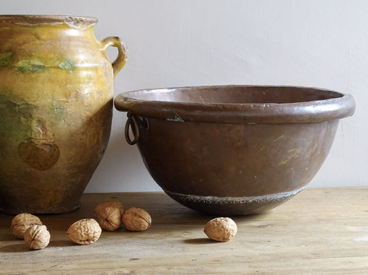 French Antique Copper Bowl for Confectioners 18th C. This timeworn copper mixing bowl has a rolled top and copper rivets to the curved base.  Pictured alongside a yellow confit pot.