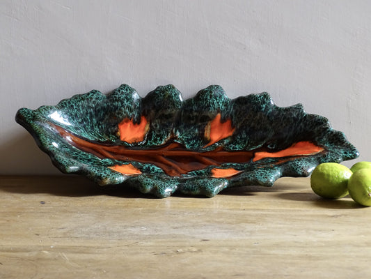Large French vintage Vallauris ceramic bowl in the shape of a leaf. It is glazed with a dark green with details in brown and orange.