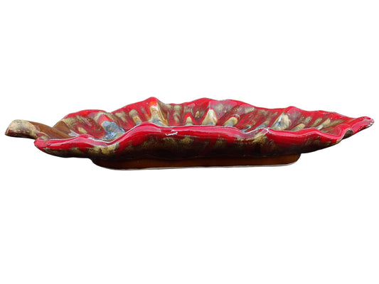French vintage Vallauris ceramic dish in a leaf design. The pottery dish is glazed in red with details in pale blue, yellow and brown