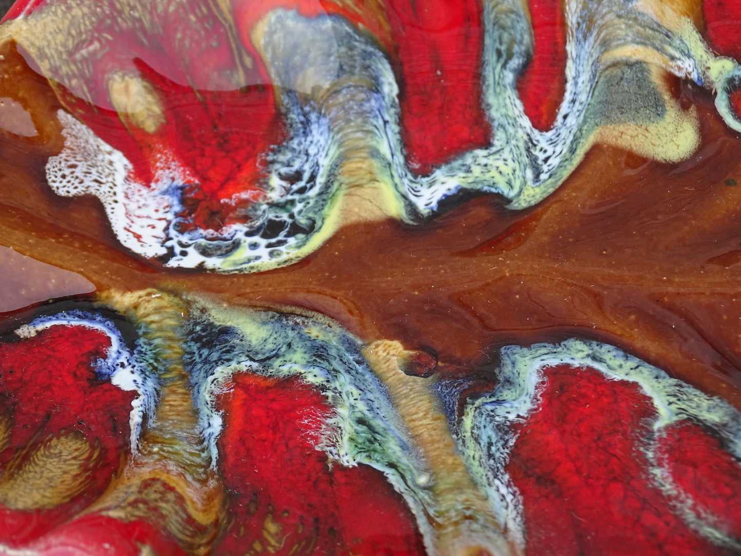 French vintage Vallauris ceramic dish in a leaf design. The pottery dish is glazed in red with details in pale blue, yellow and brown