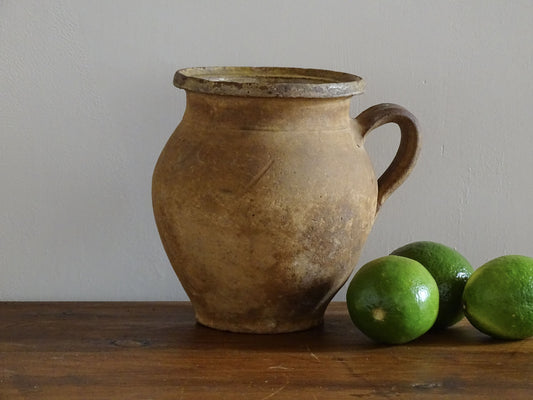 French antique terracotta jug with yellow glaze interior, rustic earthenware pitcher. 
