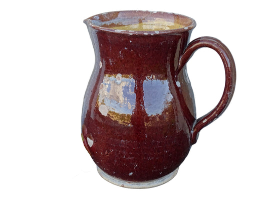 Brown French antique pottery pitcher with yellow glaze interior. Timeworn ceramic jug with handle and spout.