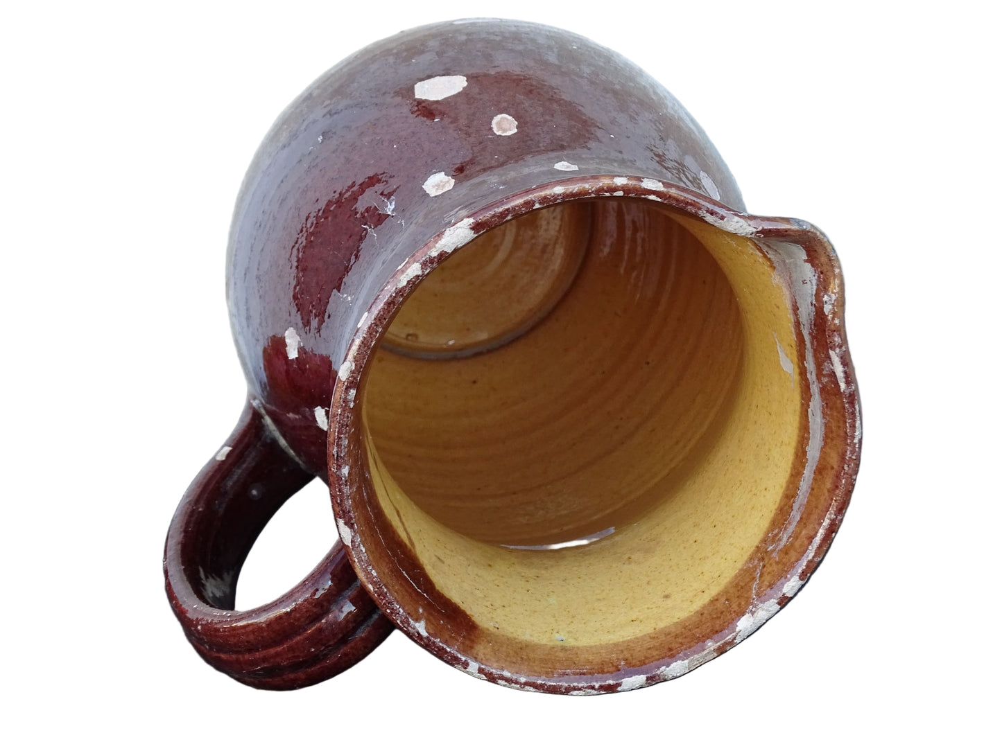 Brown French antique pottery pitcher with yellow glaze interior. Timeworn ceramic jug with handle and spout.