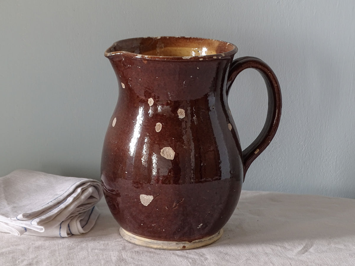 French antique ceramic pitcher with worn brown glaze and yellow glazed interior