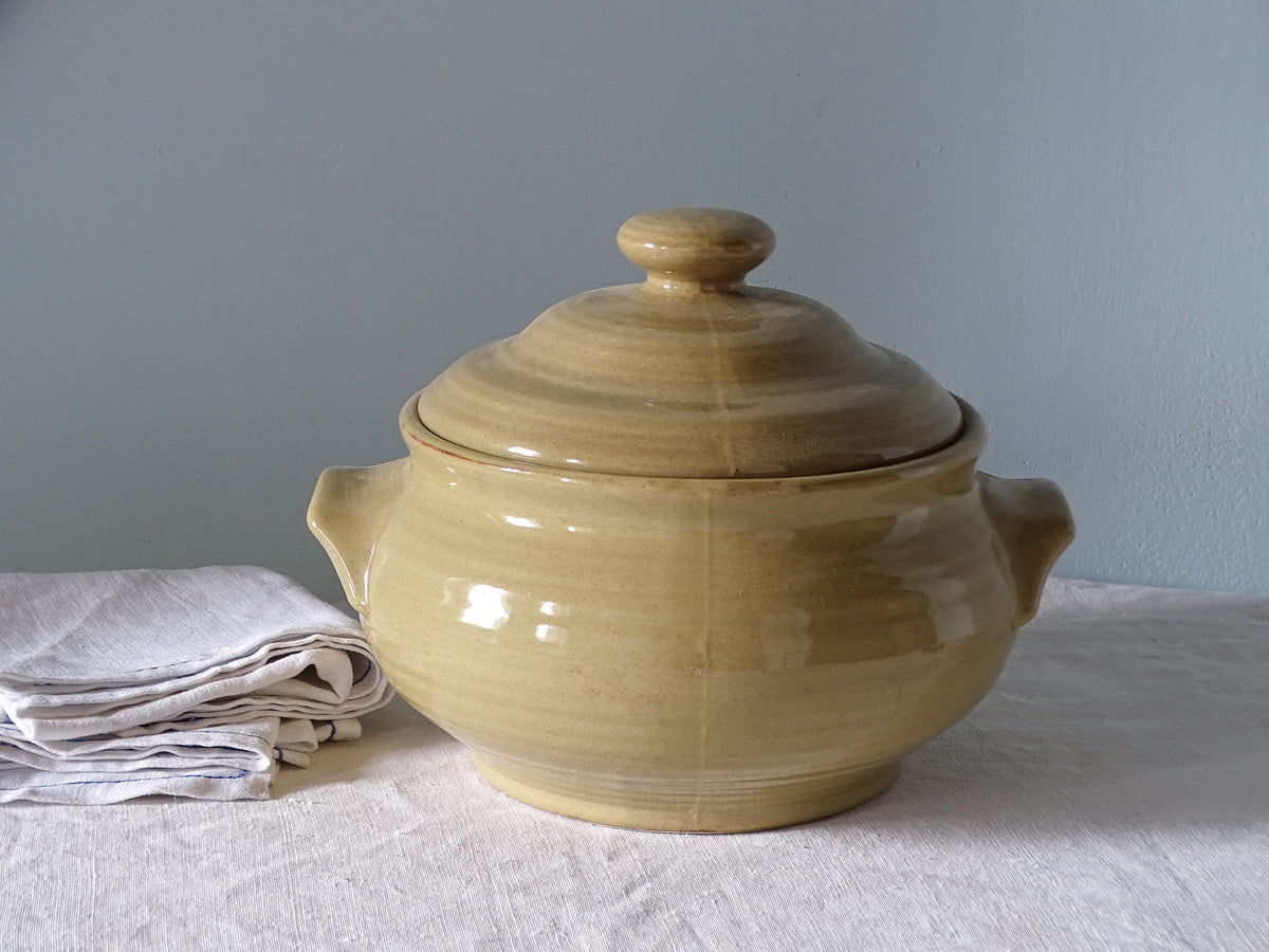 French vintage ceramic tureen with a yellow glaze, pictured with antique linen