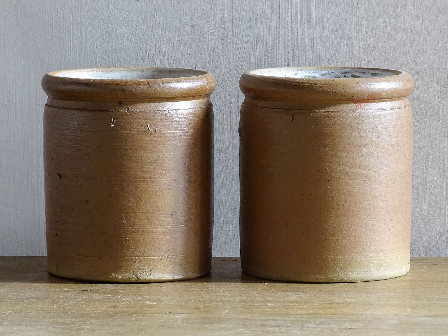 Rustic pair of French vintage stoneware pots with a brown, salt glaze. Old pottery jars with a ribbed texture.