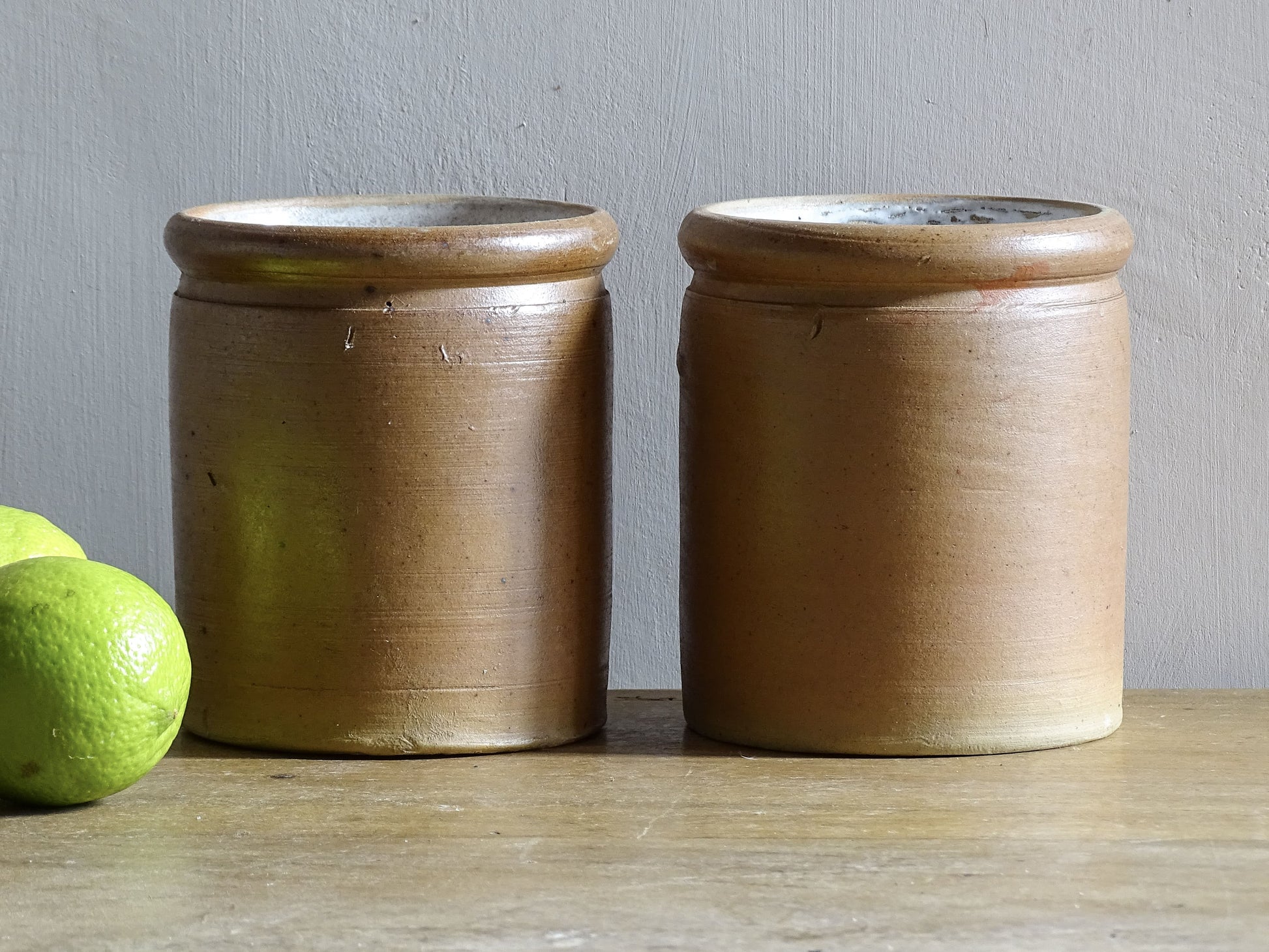 Rustic pair of French vintage stoneware pots with a brown, salt glaze. Old pottery jars with a ribbed texture.