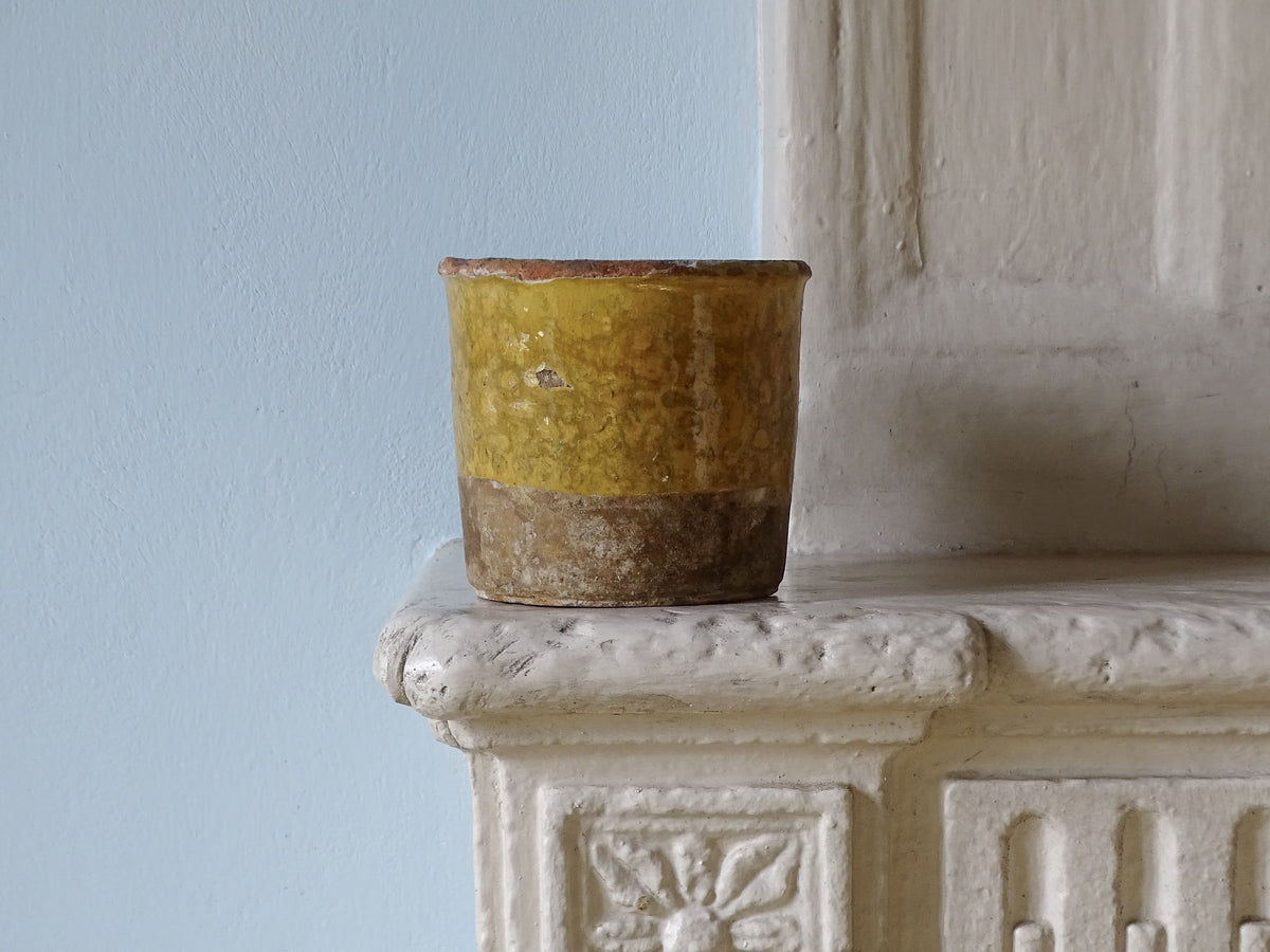 Small French antique confit pot or jar with a yellow glaze, displayed on a country house fireplace