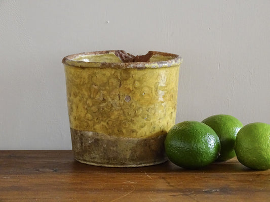 French antique yellow confit pot with patina. Aged earthenware pot with glaze.
