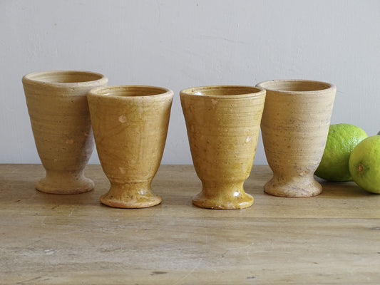 Set of four French vintage terracotta goblets. Of the four pottery cups, one has a beautiful yellow glaze, another is partially glazed and the other two are unglazed.