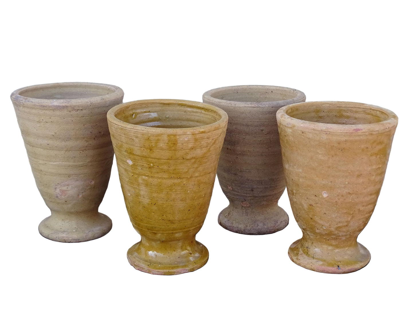 Set of four French vintage terracotta goblets. Of the four pottery cups, one has a beautiful yellow glaze, another is partially glazed and the other two are unglazed.