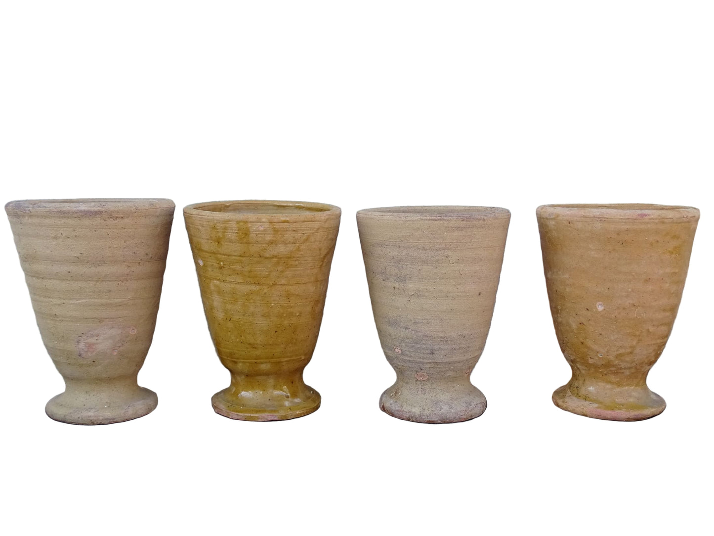 Set of four French vintage terracotta goblets. Of the four pottery cups, one has a beautiful yellow glaze, another is partially glazed and the other two are unglazed.