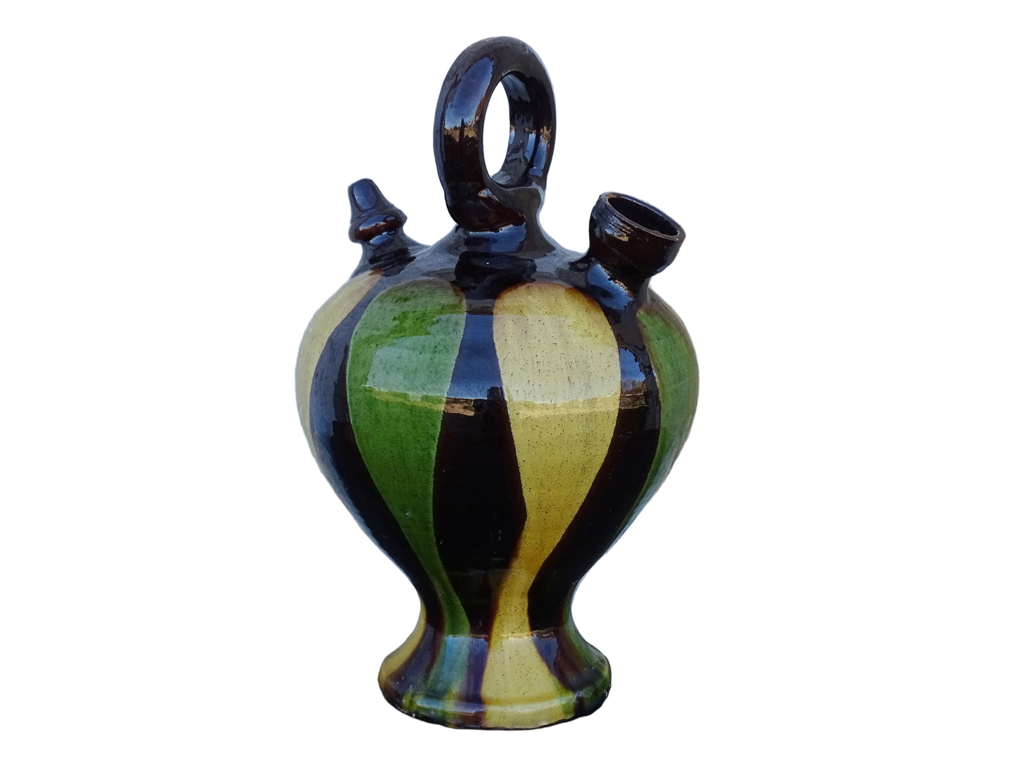 French antique pitcher or gargoulette. Terracotta jug with a green and yellow striped glaze on a dark brown background. It has a curved shape with a round handle to the top and two spouts.
