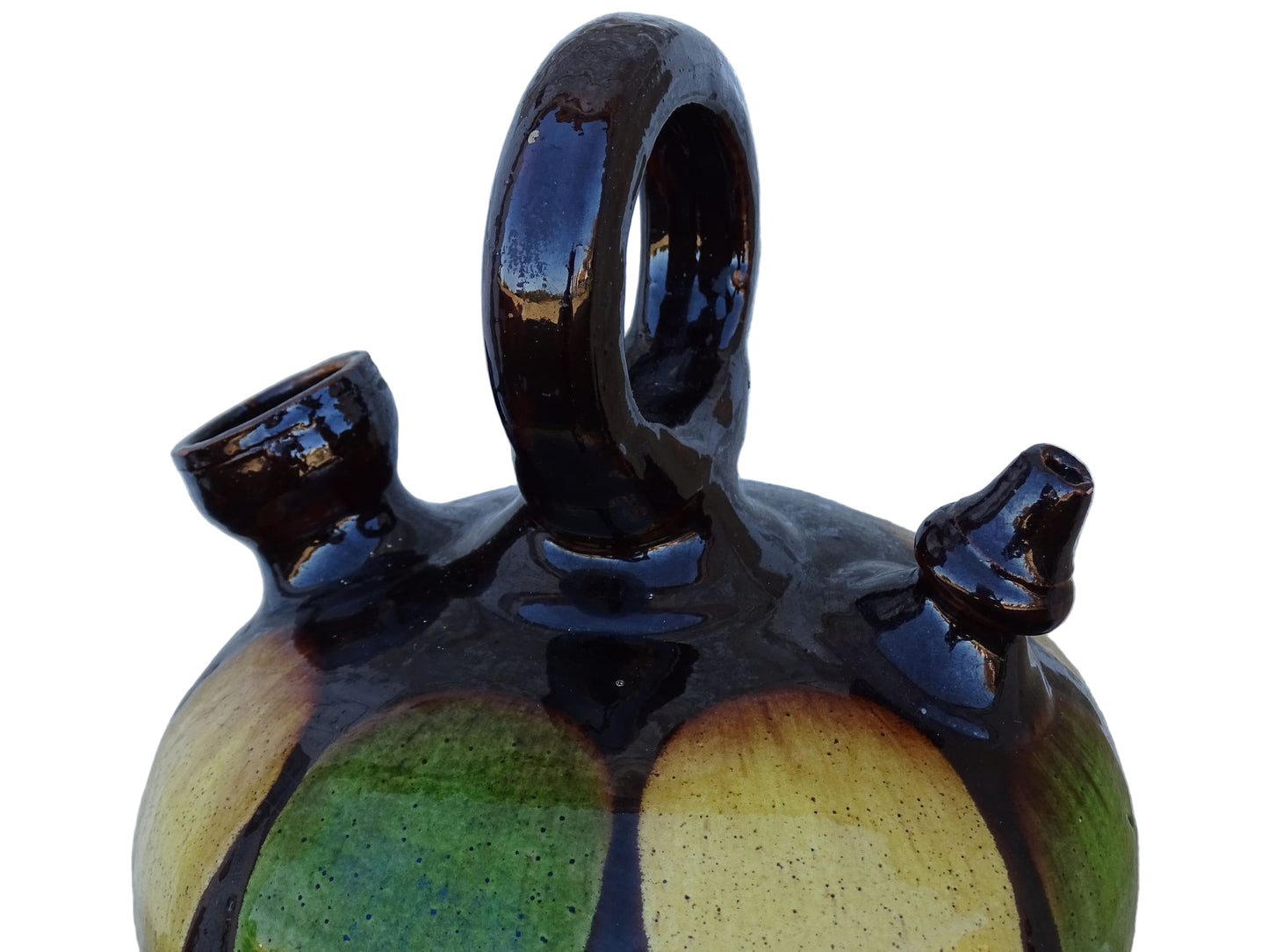 French antique pitcher or gargoulette. Terracotta jug with a green and yellow striped glaze on a dark brown background. It has a curved shape with a round handle to the top and two spouts.