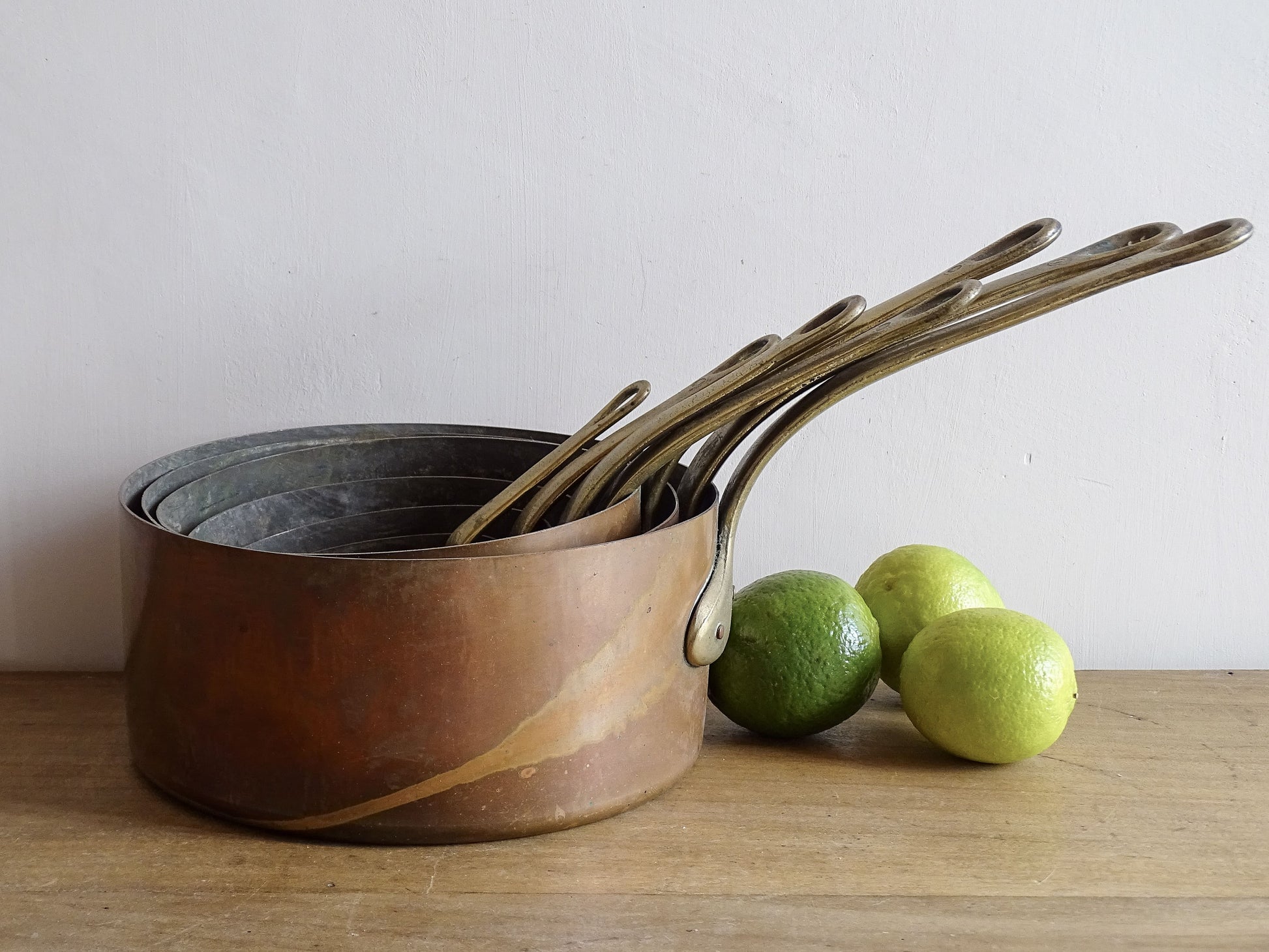 Set of seven French antique copper pans with brass handles. Tinned copper saucepans.