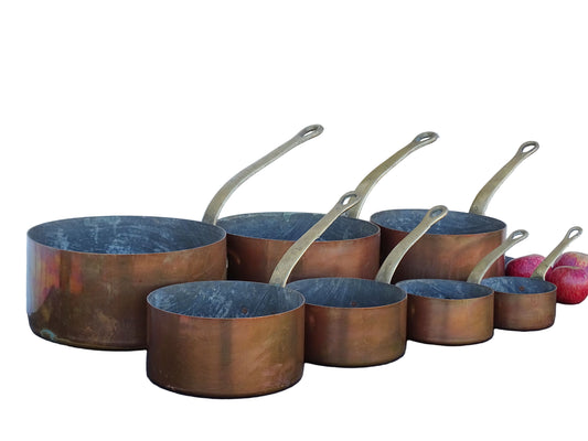 Set of seven French antique copper pans with brass handles. Tinned copper saucepans.