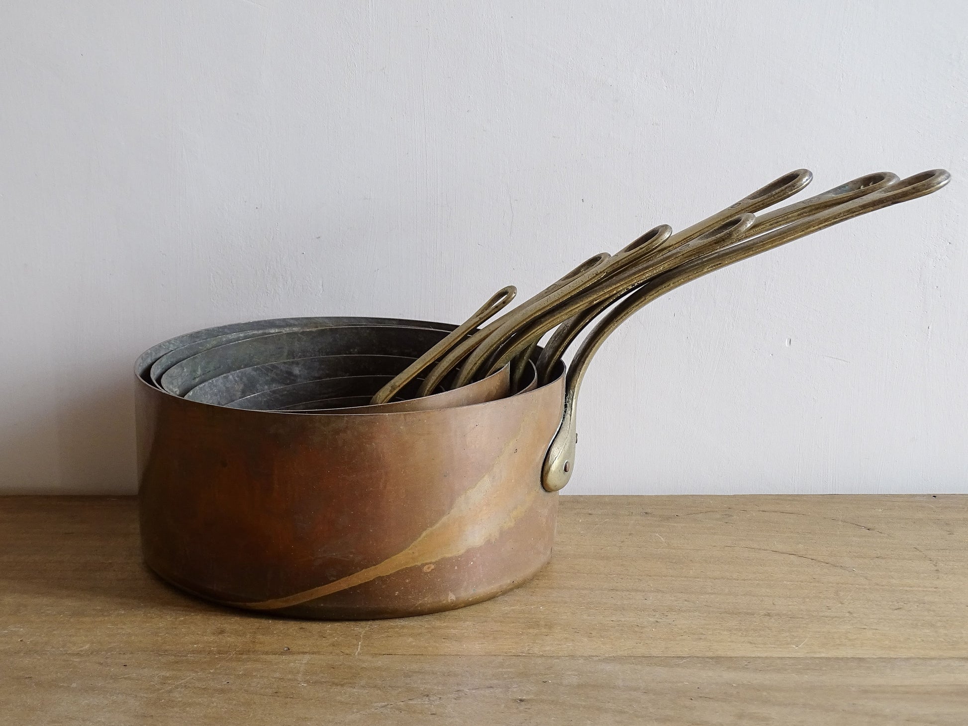 Set of seven French antique copper pans with brass handles. Tinned copper saucepans.