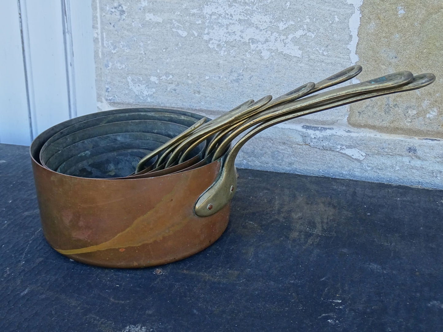 Set of seven French antique copper pans with brass handles. Tinned copper saucepans.