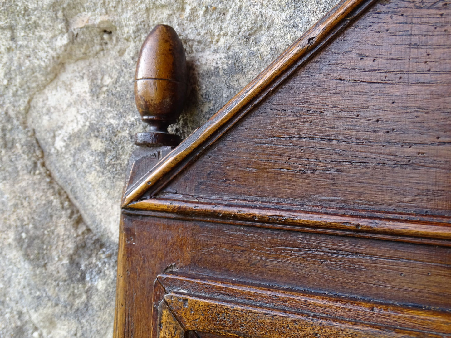 French antique wooden mirror topped with a triangular pediment decorated with a fleur de lis and two turned finial