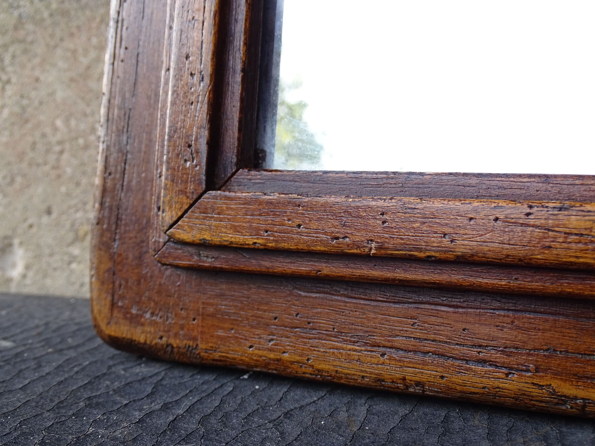 French antique wooden mirror topped with a triangular pediment decorated with a fleur de lis and two turned finial