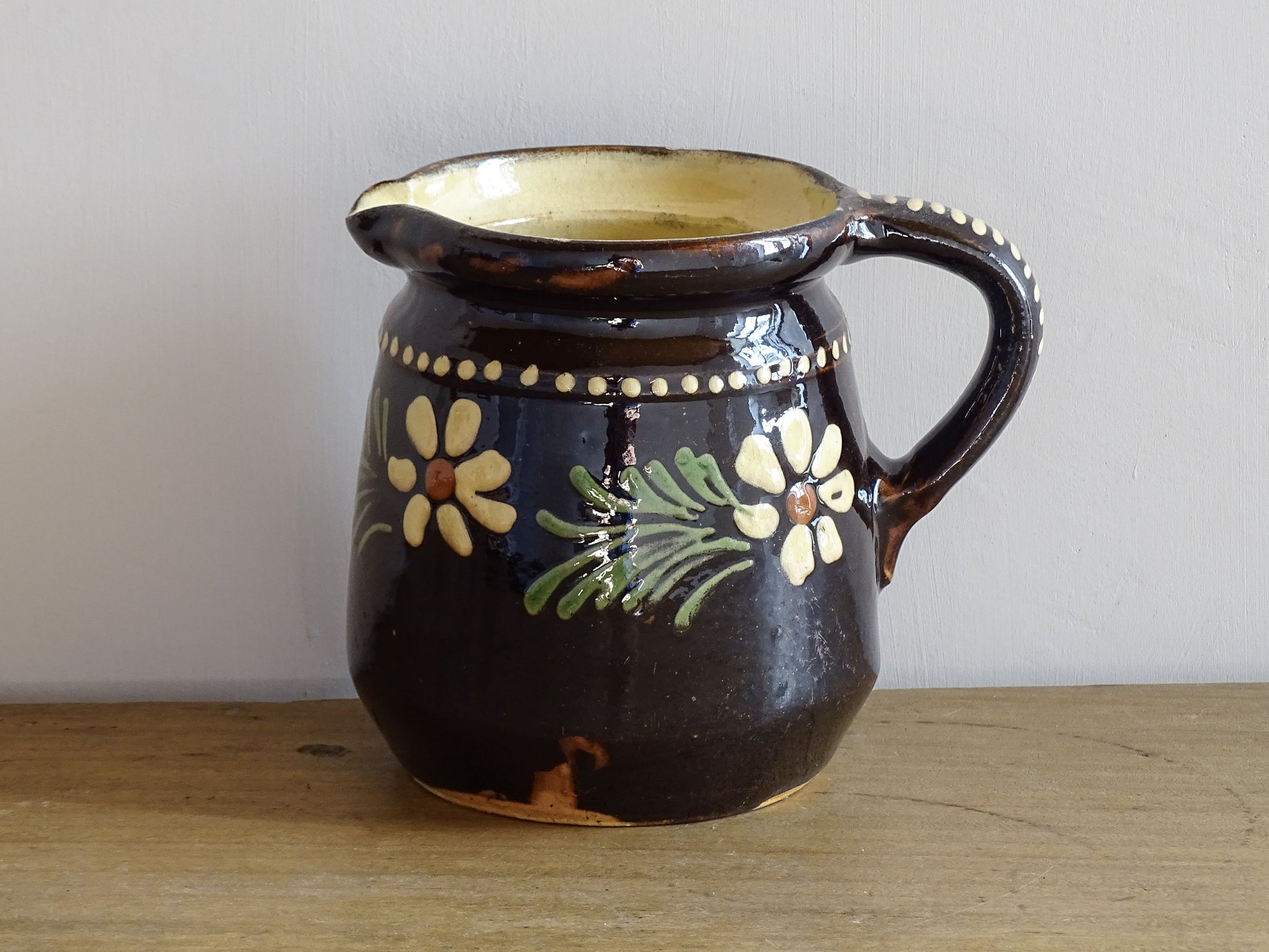 French vintage ceramic pitcher from Alsace. Pottery jug with brown glaze and hand painted with flowers, leaves and dots.