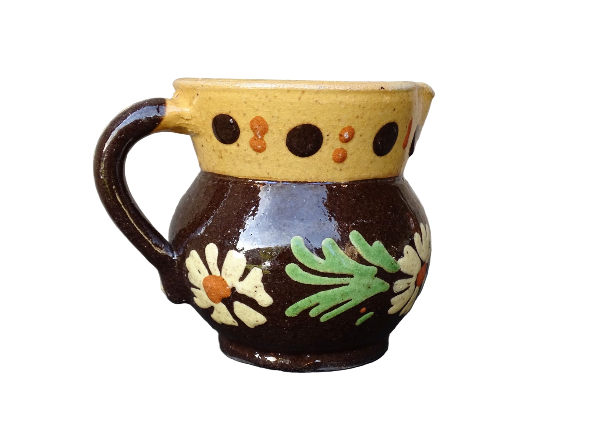 Small French vintage pottery pitcher from Alsace. Ceramic jug with a brown glaze and yellow glazed stripe around the top. It is hand painted with white flowers, green leaves and dots.
