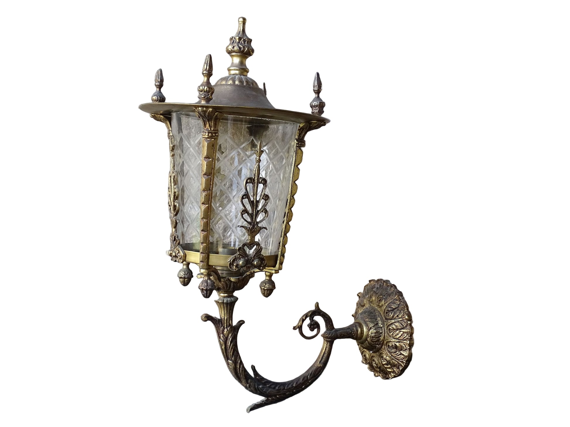 A beautiful French vintage wall light made from gilded metal with a clear cut-glass lantern. The frame has small finials to the top, leaf motifs around the sides, and an ornate scrolling arm. The glass has a diamond pattern.